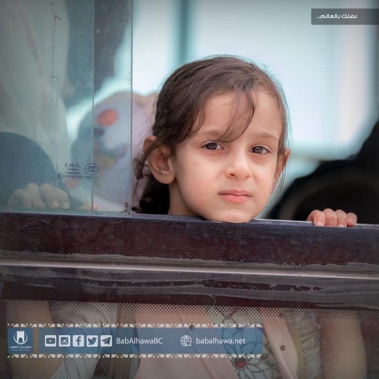 طفلة مسافرة تطل من إحدى حافلات نقل المسافرين في معبر باب الهوى - سورية